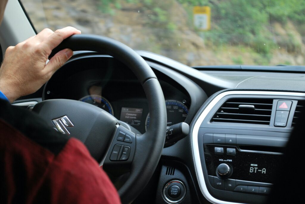 A driver in their car with their hand on the steering wheel