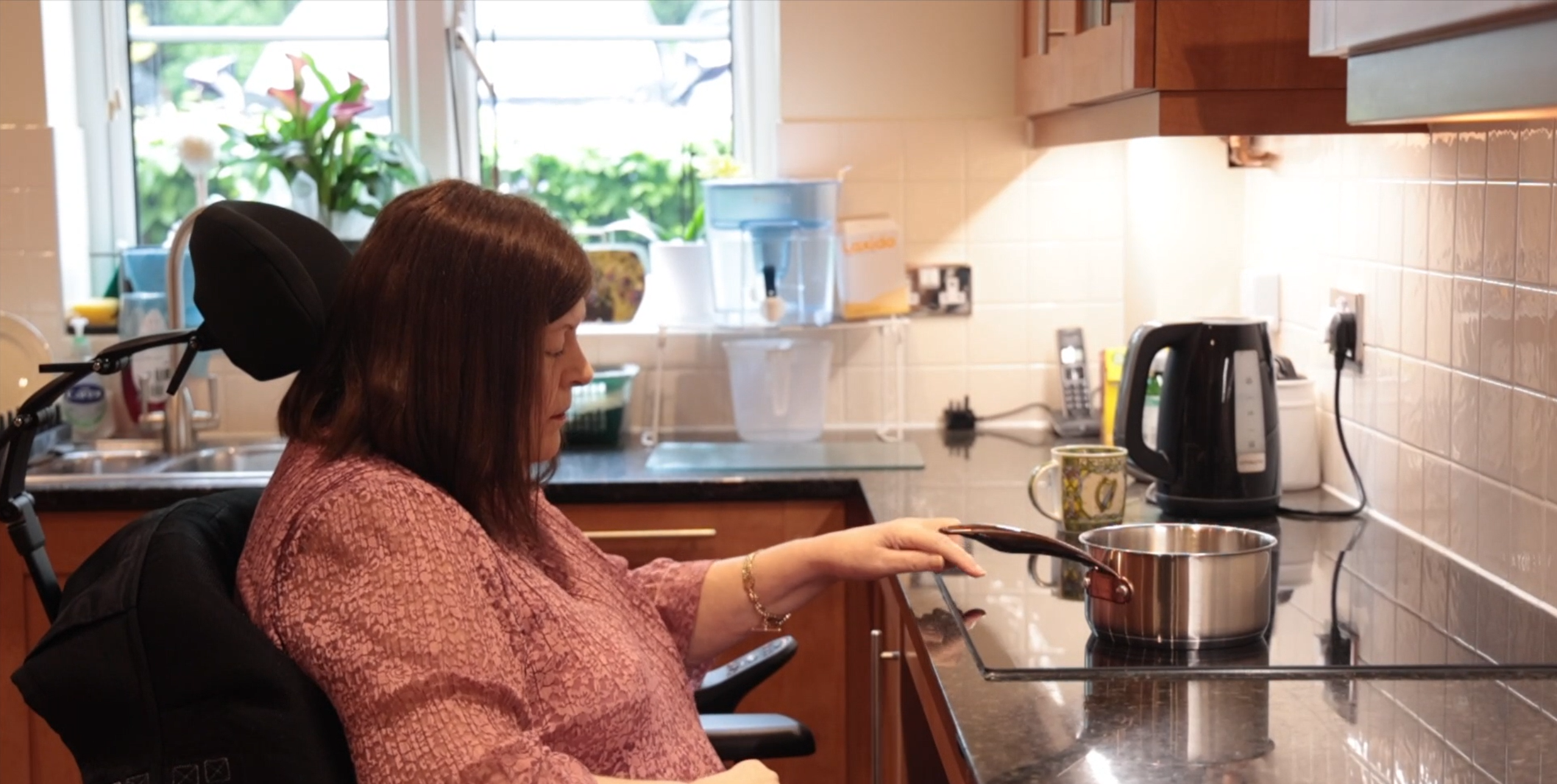 PLG - A women in a wheelchair using a hob in the kitchen